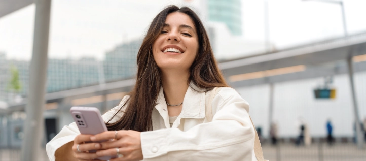 Young woman smiling while holding her phone
