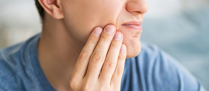 Younger man holding his jaw in pain