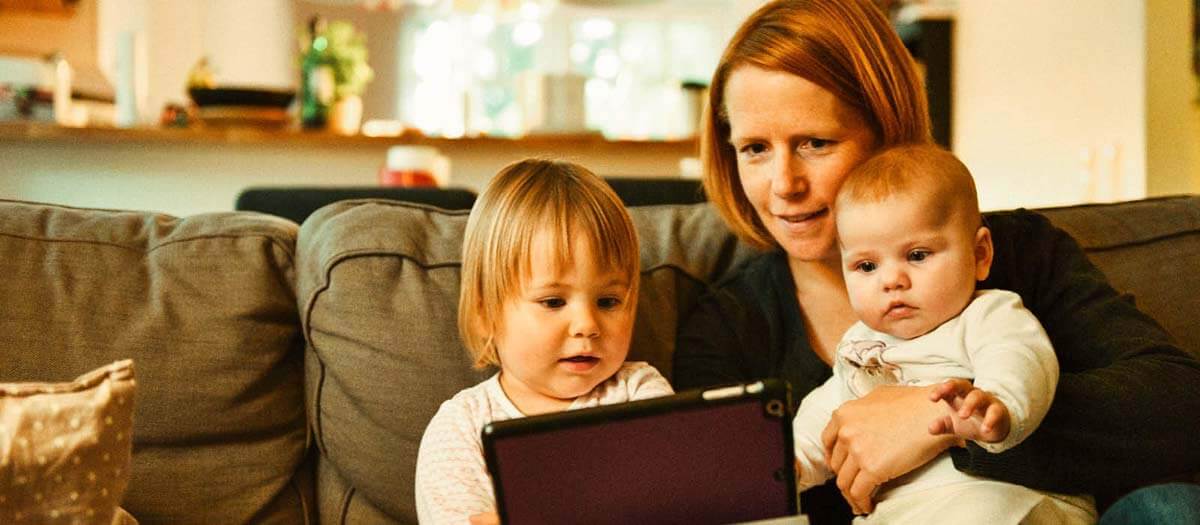 Mom and two young kids playing on an iPad