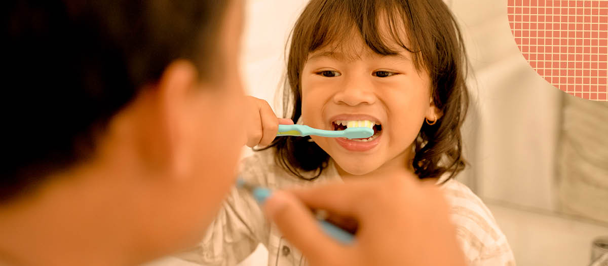 Small girl brushing her teeth while looking at her dad