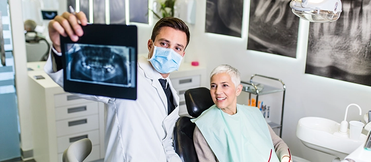 Male dentist holding up an x-ray for a patient